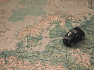 small car on a world map representing travel which is always a good topic to talk about